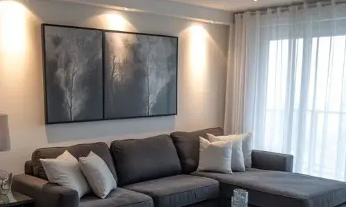 "A modern living room featuring a gray sofa paired with crisp white curtains, creating a bright and airy atmosphere."